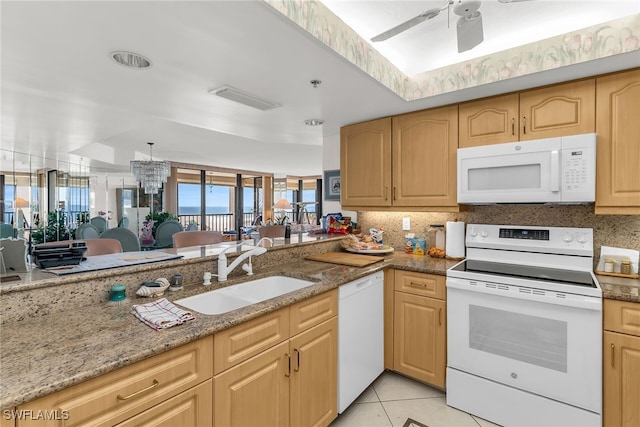 kitchen featuring white appliances, light tile patterned floors, light stone countertops, light brown cabinetry, and a sink