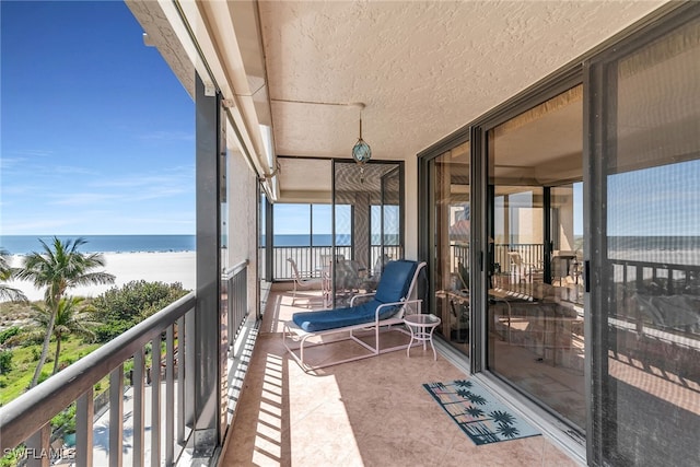 balcony with a water view and a view of the beach