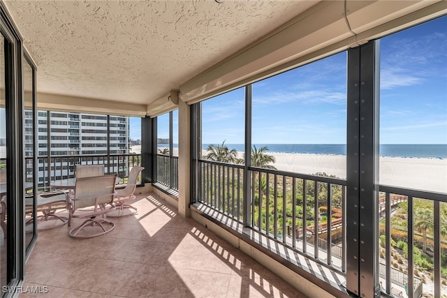 sunroom / solarium featuring a water view and a view of the beach