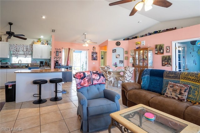 living room with vaulted ceiling, light tile patterned floors, visible vents, and a healthy amount of sunlight