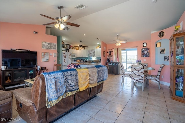 living room with light tile patterned floors, baseboards, visible vents, a ceiling fan, and lofted ceiling