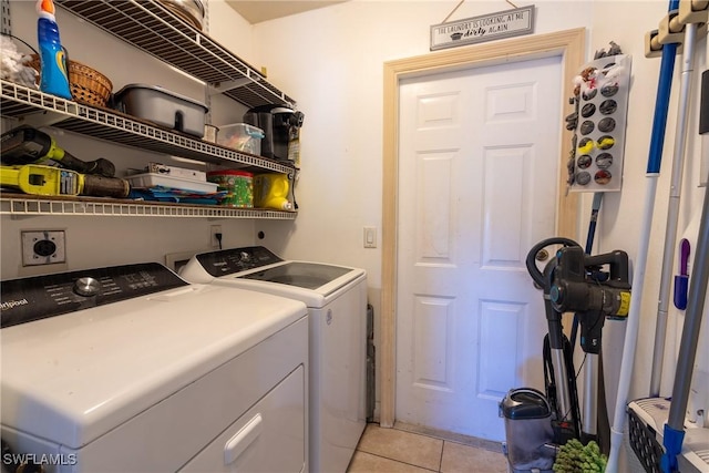 clothes washing area with washing machine and dryer, laundry area, and light tile patterned floors