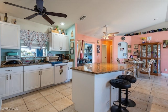 kitchen featuring light tile patterned floors, white cabinets, dishwasher, a breakfast bar, and a center island