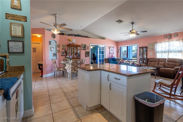 kitchen featuring lofted ceiling, light tile patterned floors, a kitchen island, visible vents, and white cabinetry