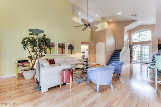 living area featuring visible vents, ceiling fan, light wood finished floors, and stairs