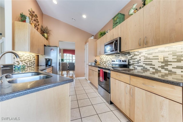 kitchen featuring light tile patterned floors, appliances with stainless steel finishes, light brown cabinets, vaulted ceiling, and a sink