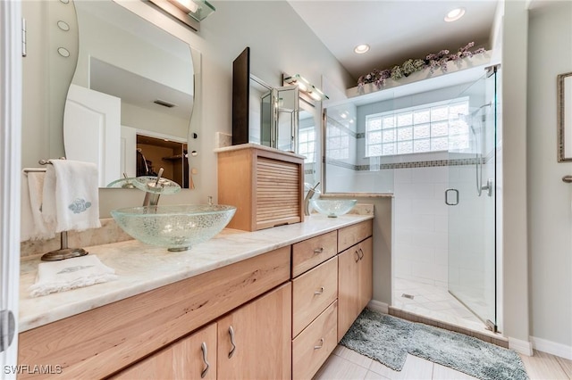 full bath with visible vents, a sink, a shower stall, and double vanity