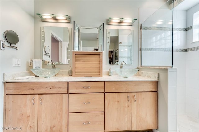 full bathroom featuring double vanity, a walk in shower, and a sink