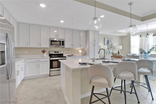 kitchen with recessed lighting, light countertops, ornamental molding, appliances with stainless steel finishes, and a center island with sink