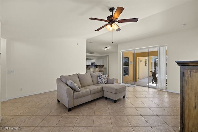 living area with lofted ceiling, light tile patterned floors, a ceiling fan, and baseboards