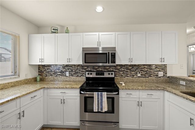 kitchen with light stone counters, decorative backsplash, appliances with stainless steel finishes, and white cabinetry