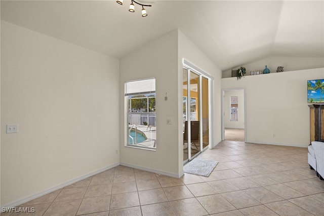 interior space featuring light tile patterned floors, baseboards, and vaulted ceiling