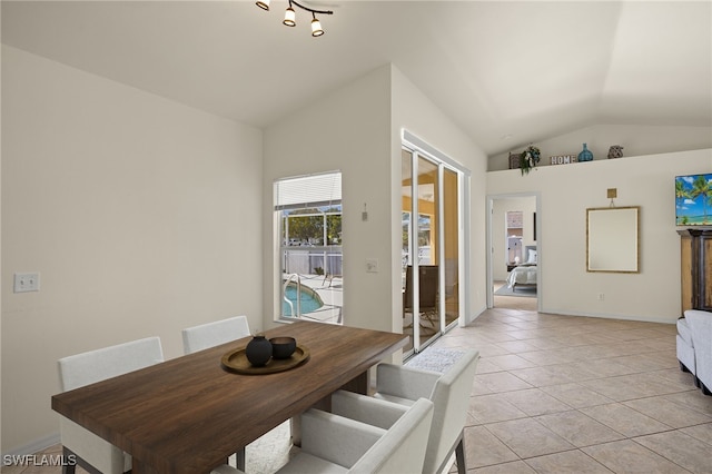 dining room with light tile patterned floors, baseboards, and vaulted ceiling