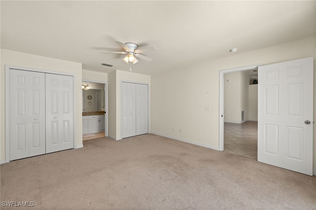 unfurnished bedroom featuring visible vents, two closets, ceiling fan, baseboards, and light carpet