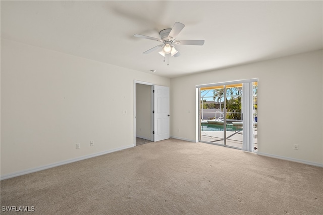 carpeted spare room featuring baseboards and ceiling fan