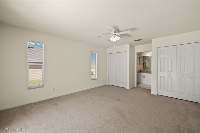 unfurnished bedroom with visible vents, multiple closets, multiple windows, and light carpet