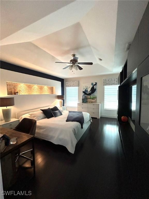 bedroom with visible vents, a raised ceiling, a ceiling fan, and wood-type flooring