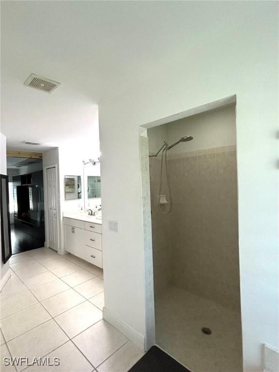 bathroom with visible vents, baseboards, tiled shower, tile patterned floors, and vanity