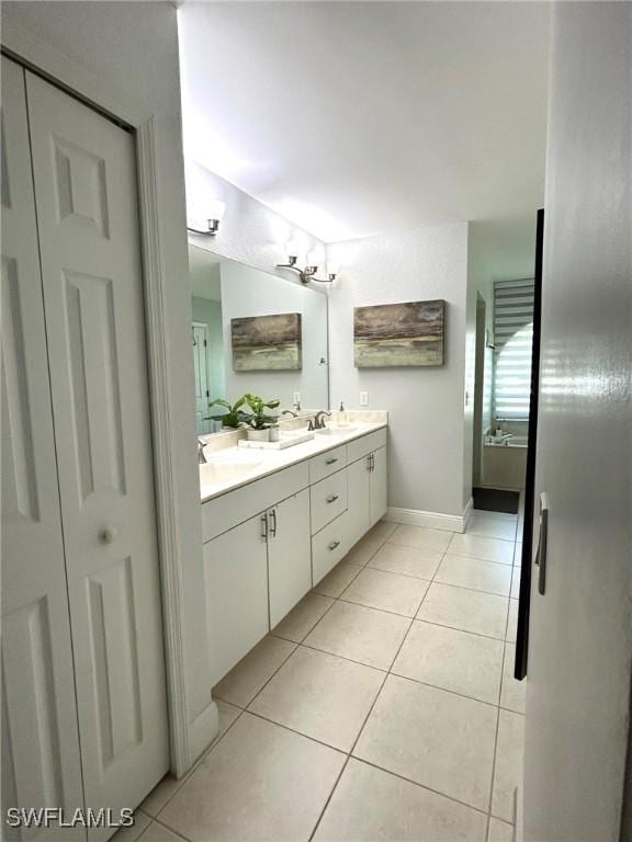 full bathroom with tile patterned floors, baseboards, double vanity, and a sink