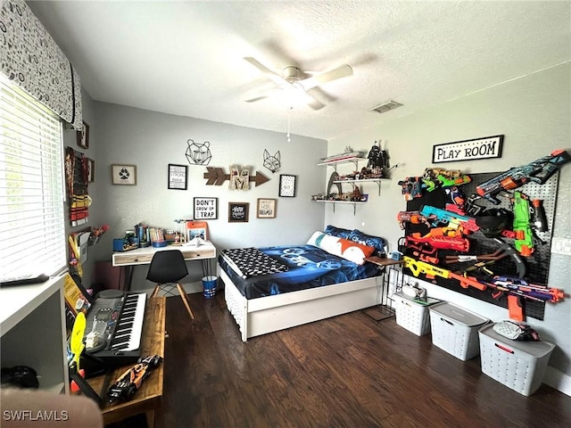 bedroom featuring a ceiling fan, wood finished floors, visible vents, and a textured ceiling