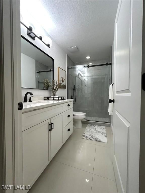 bathroom with a stall shower, toilet, vanity, and a textured ceiling