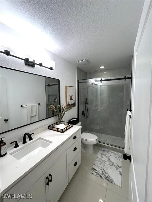 bathroom featuring vanity, a shower stall, toilet, and a textured ceiling