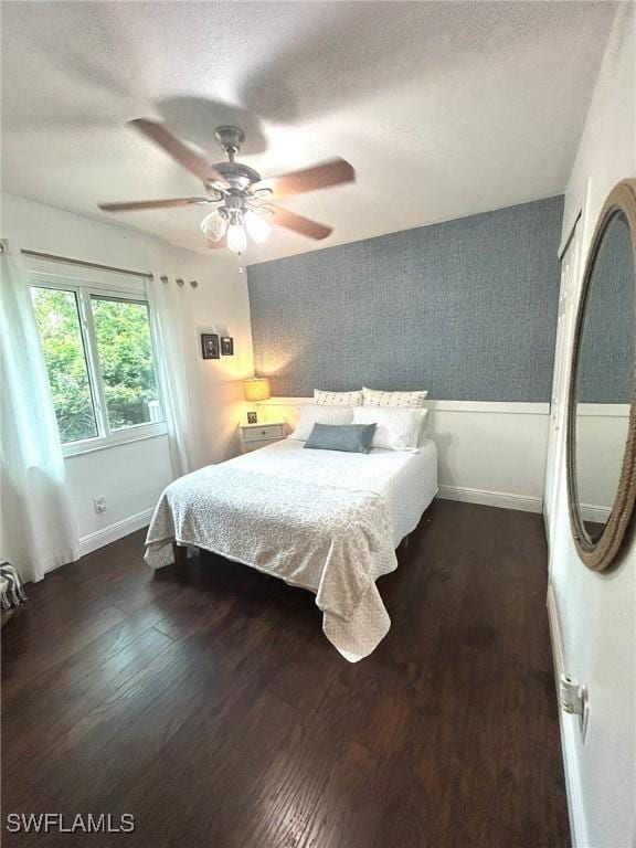 bedroom with baseboards, a textured ceiling, ceiling fan, and dark wood-style flooring