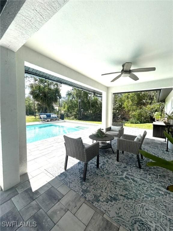 outdoor pool with a patio area, an outdoor hangout area, and a ceiling fan