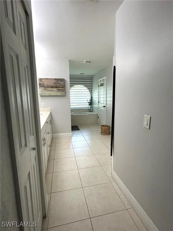 bathroom featuring baseboards, a bath, vanity, and tile patterned flooring