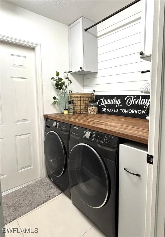 laundry area featuring cabinet space, a textured ceiling, tile patterned flooring, and washer and clothes dryer