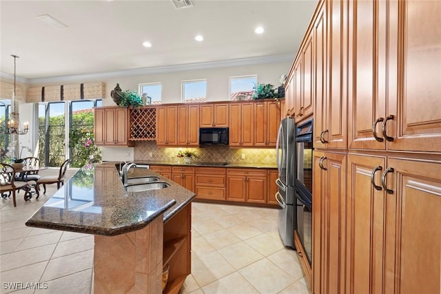 kitchen featuring brown cabinets, a notable chandelier, tasteful backsplash, a sink, and black appliances