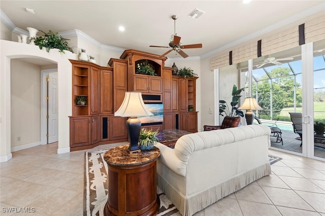 living area featuring arched walkways, a sunroom, visible vents, a ceiling fan, and ornamental molding