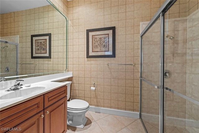 bathroom featuring tile walls, toilet, a stall shower, vanity, and tile patterned floors