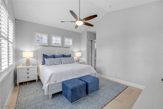 bedroom featuring ceiling fan, light wood-style flooring, baseboards, and vaulted ceiling