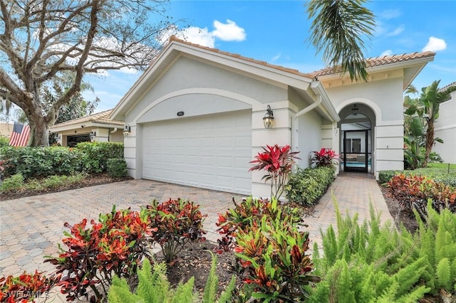 mediterranean / spanish home featuring a garage, decorative driveway, and stucco siding