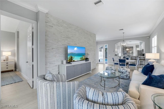 living room with plenty of natural light, an accent wall, visible vents, and ornamental molding