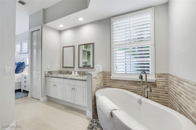 full bath with visible vents, a freestanding tub, vanity, and recessed lighting