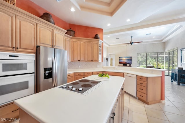 kitchen featuring a peninsula, white appliances, open floor plan, decorative backsplash, and a raised ceiling