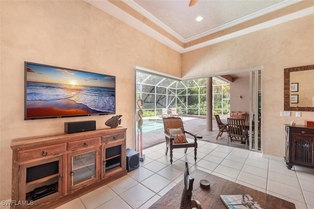 living room featuring a sunroom, ceiling fan, ornamental molding, tile patterned floors, and a high ceiling