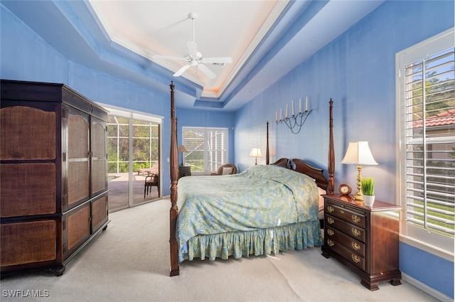 carpeted bedroom featuring access to exterior, a tray ceiling, baseboards, and a ceiling fan