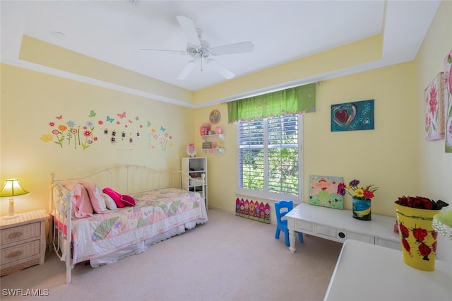 bedroom with a tray ceiling, a ceiling fan, and carpet flooring