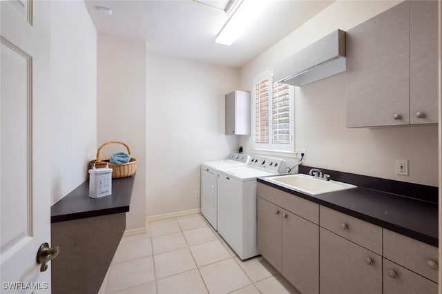 clothes washing area with light tile patterned floors, separate washer and dryer, a sink, baseboards, and cabinet space