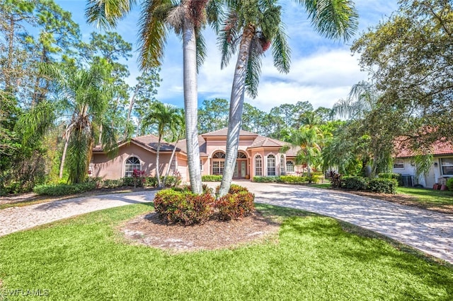 mediterranean / spanish home with a front yard, driveway, and stucco siding