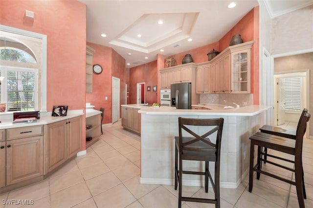 kitchen with tasteful backsplash, stainless steel fridge with ice dispenser, glass insert cabinets, a breakfast bar, and a peninsula