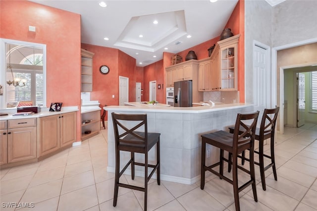 kitchen featuring glass insert cabinets, stainless steel fridge, a peninsula, and a kitchen bar