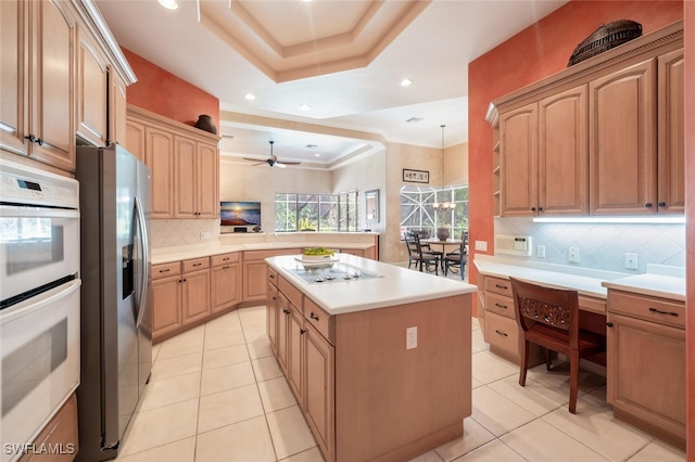 kitchen featuring white double oven, a center island, a tray ceiling, electric stovetop, and stainless steel refrigerator with ice dispenser