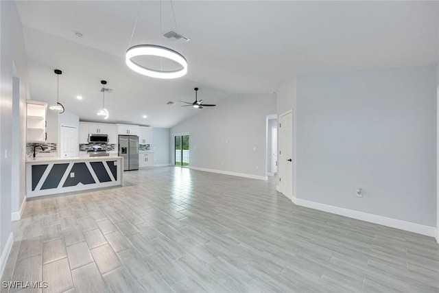 unfurnished living room featuring ceiling fan, lofted ceiling, a sink, visible vents, and light wood-style floors