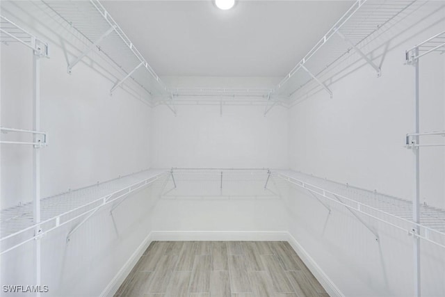 walk in closet with wood finished floors