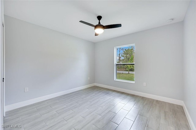 empty room with light wood finished floors, baseboards, and a ceiling fan