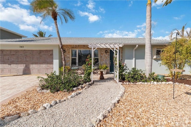 single story home with driveway, roof with shingles, an attached garage, a pergola, and stucco siding